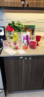 Group view of all vases, artificial flowers, book, paper goods and small accessories on countertop