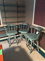 Three green wooden bar stools in corner view