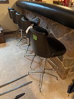 Side view of four black swivel bar stools at bar