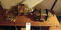 Both brass lantern sconces on shelf showing overall design and wiring