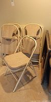 Four cushioned folding chairs stacked together