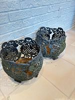 Two cast iron scroll lattice planters side by side showing overall form and rusted interiors