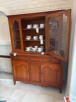 Full view of cabinet with upper glass door open showing three shelves and lower drawer/doors