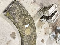 Curved concrete seat slab with moss, two pedestal legs nearby