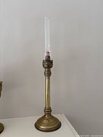 Full view of brass lantern with glass chimney standing on base