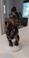 Front view of glossy brown porcelain bear cub figurine on white base