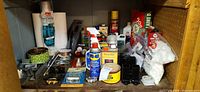 Shelf with assorted cans, bottles, wire spools, towels and hardware