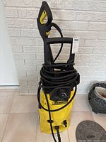 Front view of yellow Karcher electric pressure washer showing hose, cord and controls