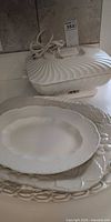 Stack of three white platters and ceramic electric warmer with cord