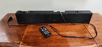 Front view of Samsung sound bar with remote and power cord