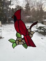 Front view of stained glass cardinal and flower panel hanging against window