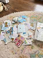 Loose assortment of stamps spread on rug with additional packet