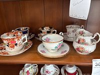Shelf showing all five teacup & saucer sets plus stacked creamer and sugar bowl