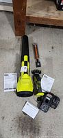 All items overview: leaf blower, grass shear body, two blade attachments, battery, charger, manuals