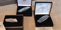 Three Zippo pocket knives in open gift boxes on carpet