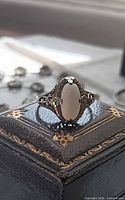 Front view of opal filigree ring on decorative box