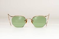 Front view of rimless hexagon sunglasses showing green lenses and gold bridge