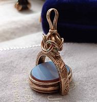 Front angled view showing engraved gold frame, sardonyx face, bail detail