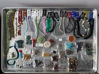 Full tray view of bead strands on cards and multiple zip bags of loose beads and findings