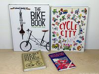 All four bicycle-related books laid out on table