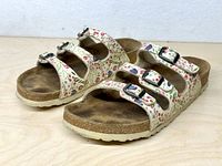Left side view of both sandals showing floral uppers, buckles, and footbeds
