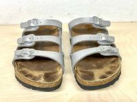 Front view of both sandals showing three silver straps and footbed wear