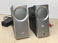 Front view of both speakers, power adapter visible