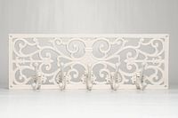 Front view of ornate white cast iron wall rack with five hooks