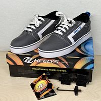 Pair of Heelys shoes on top of box with wheels, plugs, tool visible