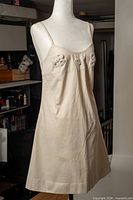 Full front view of cream cotton spaghetti-strap dress on mannequin