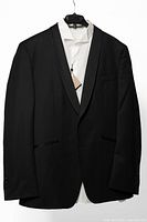 Front view of black tuxedo jacket over white shirt on hanger