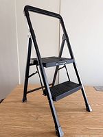 Ladder fully opened showing frame, two steps, branding