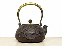 Full view of teapot showing brass handle and lid