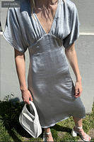 Front view of misty blue satin midi dress on model, white handbag not included
