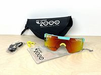 Front view of sunglasses with accessories: case, pouch, spare nose piece, strap