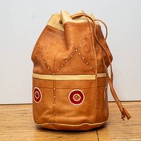 Full view of tan leather bucket bag with drawstring top