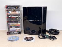 PlayStation 3 console with game stack, loose discs and power cord