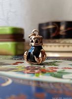 Front view of charm showing glass body, gold cap and claw feet