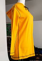 Side view of yellow hooded dress on mannequin showing seam details and hood