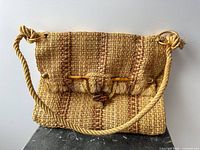Front view of woven straw shoulder bag showing overall design