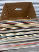 Cardboard box with large stack of vinyl records side view