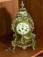 Front view of mantle clock showing dial, painted scene, ormolu mounts, key placed in front