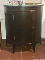 Front view of demi-lune mahogany cabinet with glass top