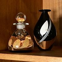 Both Caithness ink bottle and Kosta vase on shelf