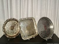 Three silver plated trays standing side by side