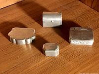 Group view of four pewter boxes on wood surface