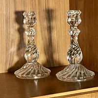 Pair of clear pressed glass candlesticks on shelf