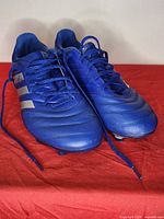 Top view of both cleats showing toe box, laces, and three-stripe branding