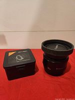 Lens and adapter with box on red surface