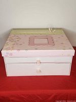 Top and front view showing floral lid, ribbon photo frame and two drawers